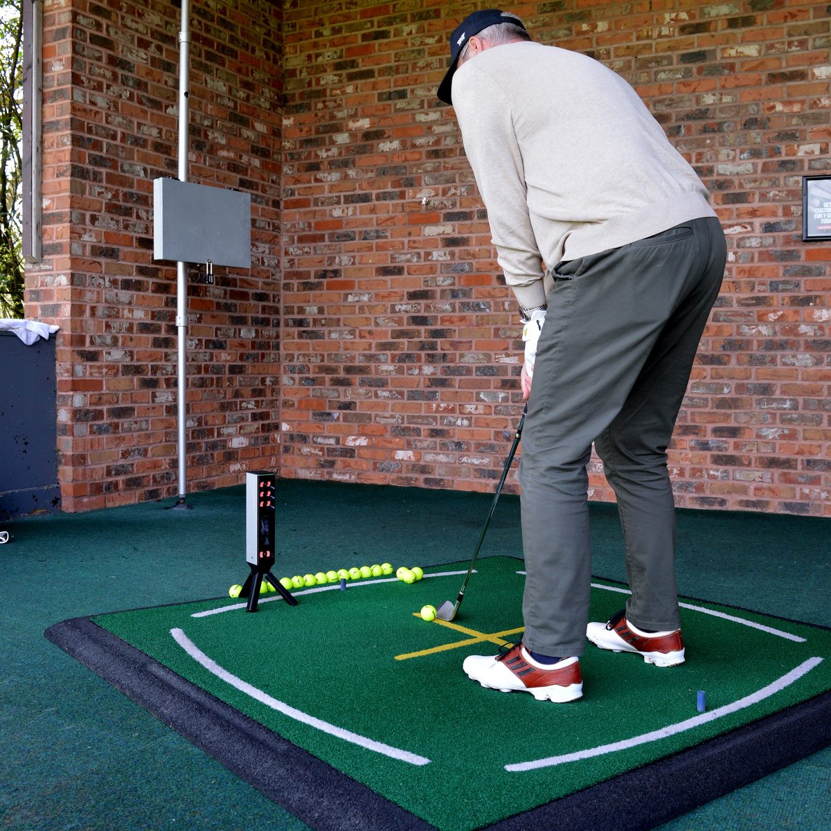 マットの横にSQUARE GOLF OMNIを設置して打っている様子